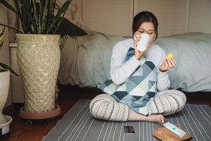 一名女子拿着月经杯在她的卧室里喝水＂width=