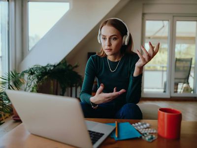 Young woman sitting in the living room at home and having a video call online therapy session with her therapist