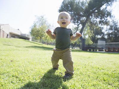 Baby boy learning to walk on grass