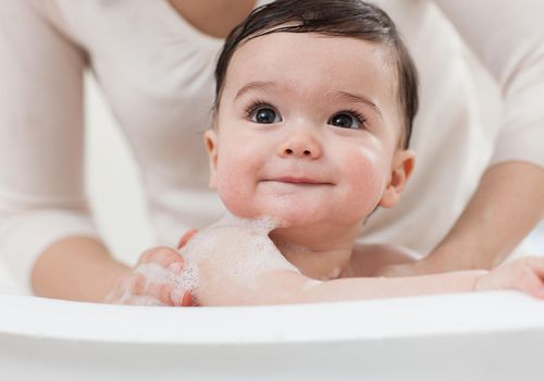 Mother's hands bathing baby