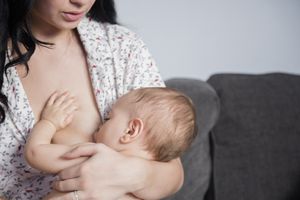 白人母亲在沙发上哺乳婴儿儿子