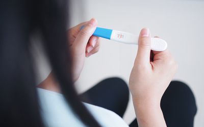 妇女在家里拿着验孕棒华体会体育官方人口