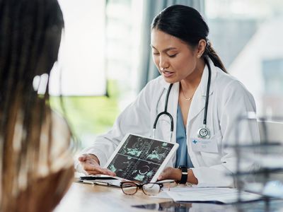 Closeup shot of a doctor showing a patient ultrasound scans on a digital tablet in her office