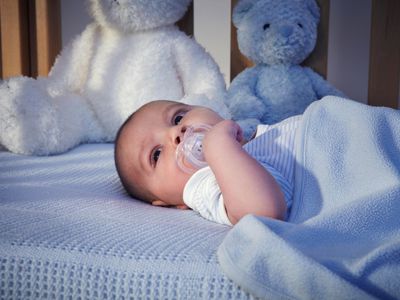Baby boy and teddy bears in crib at night