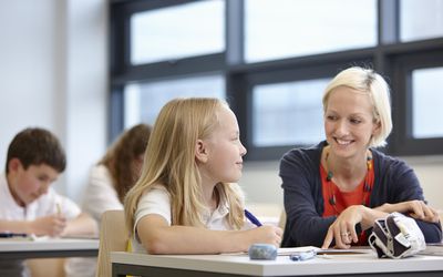 老师working with schoolgirl in classroom