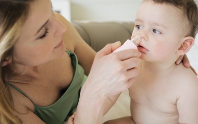 A mother suctioning her baby's nose