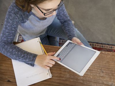 Teenage girl working on tablet and taking notes