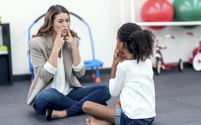 成年女性治疗师指导年轻女孩进行语言治疗