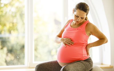 中年孕妇抱着她的手臂在她的乳房下和她的背部