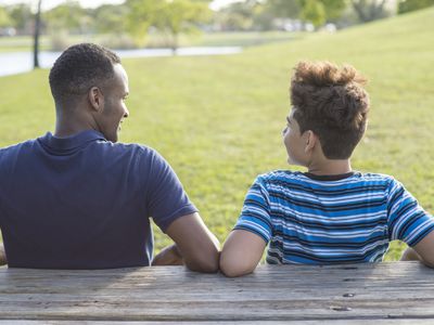 Father and son sitting at table in park