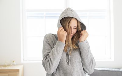 年轻的少年把脸藏在卫衣里