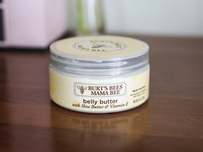 Tub of Burt's Bees Belly Butter displayed on a wooden surface