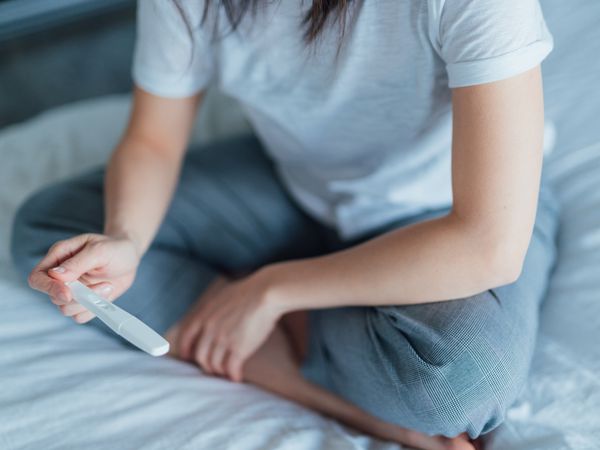 Close up shot of a young woman holding home pregnancy test.