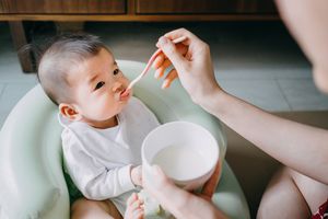 母亲第一次在家里用固体食物喂婴儿——库存照片