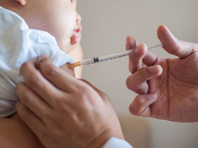 A doctor is injecting a vaccine to a baby boy