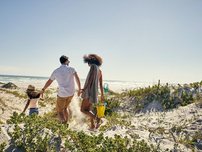 Rearview shot of a little girl and her parents spending time together at the beach