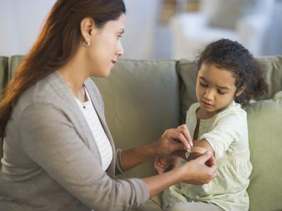 Mother applying Band-Aid on daughter's arm