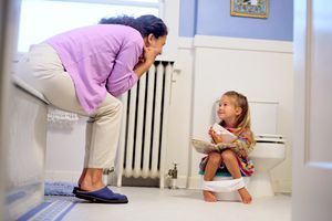 Girl reading a book on a potty chair