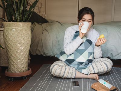 Woman holding a menstrual cup while drinking water in her bedroom