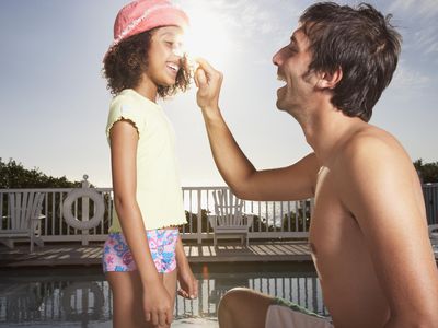 Man and girl applying sun block to noses