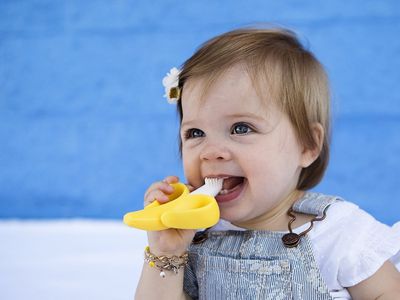 Toddler holding a Baby Banana Toothbrush in their mouth