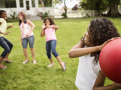 Girls playing dodgeball in backyard