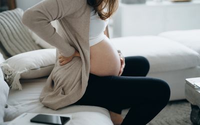 一个女人坐在沙发上抱着她怀孕的肚子