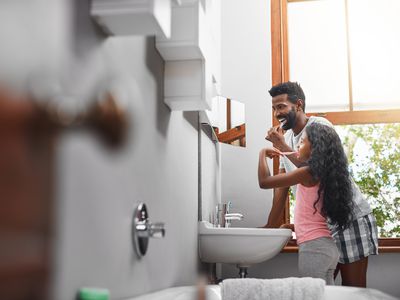 dad and daughter brushing teeth together