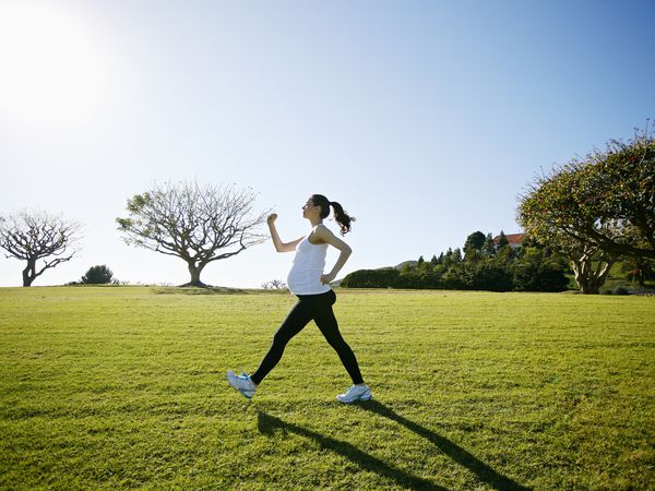 A pregnant person walks across a grassy field