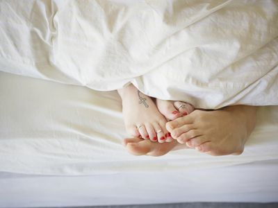 Young couple in bed, feet touching, allusion to female orgasm and fertility