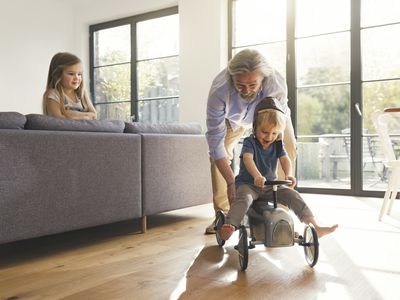 Grandfather playing with grandchildren, sitting on toy car