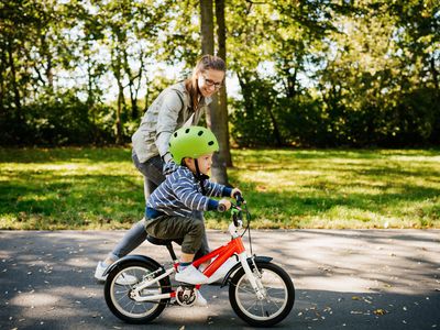 Mother teaching little boy how to ride a bike.