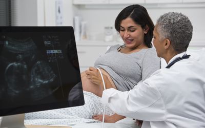 Black doctor giving pregnant patient ultrasound
