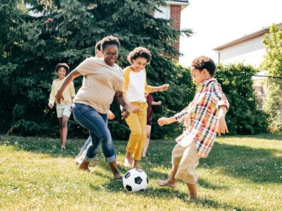 A mother playing soccer with her kids