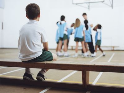 Kids in gym class - one boy sitting on bench