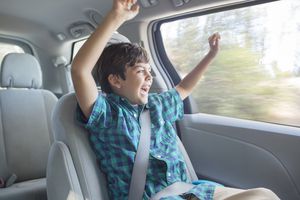 Enthusiastic boy cheering in back seat of car
