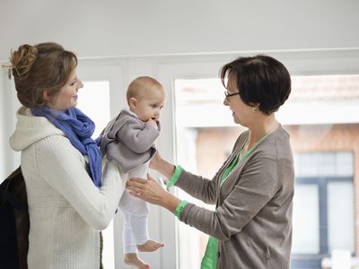 Mother handing baby over to nanny