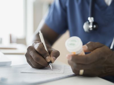 Close up of doctor with bottle writing prescription