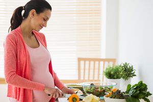 Pregnant woman making salad.