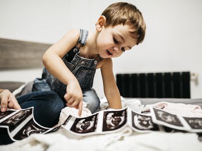 Little boy looking at ultrasound scans of his pregnant mother