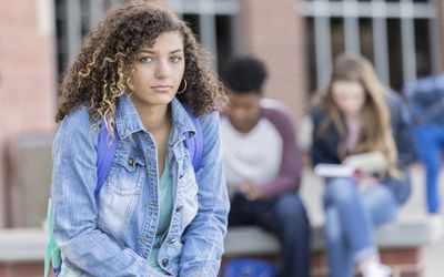 Sad-looking college student with classmates in background