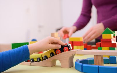 Mom and boy are playing with train and wooden blocks