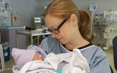 Preemie mom holding preemie baby in NICU
