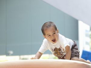 蹒跚学步的孩子在体育馆的垫子上爬行