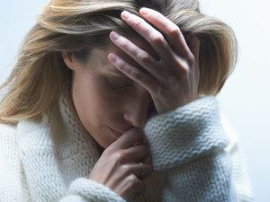 穿着毛衣的女人抱着她的头，因为不孕而感到沮丧和焦虑