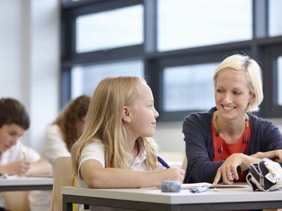 Teacher working with schoolgirl in classroom