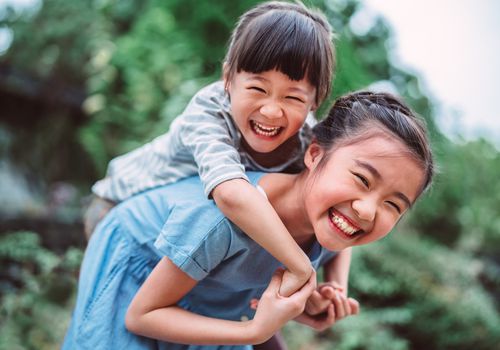 在公园里，女孩高兴地背着她的小妹妹