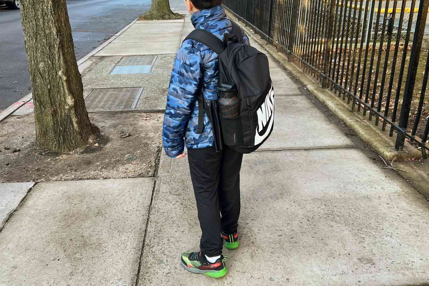 Person wearing Nike Elemental Backpack and walking on concrete side walk