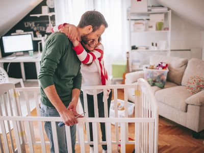 expecting father helping wife build crib for baby