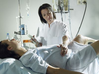Midwife checking woman's pregnancy in hospital